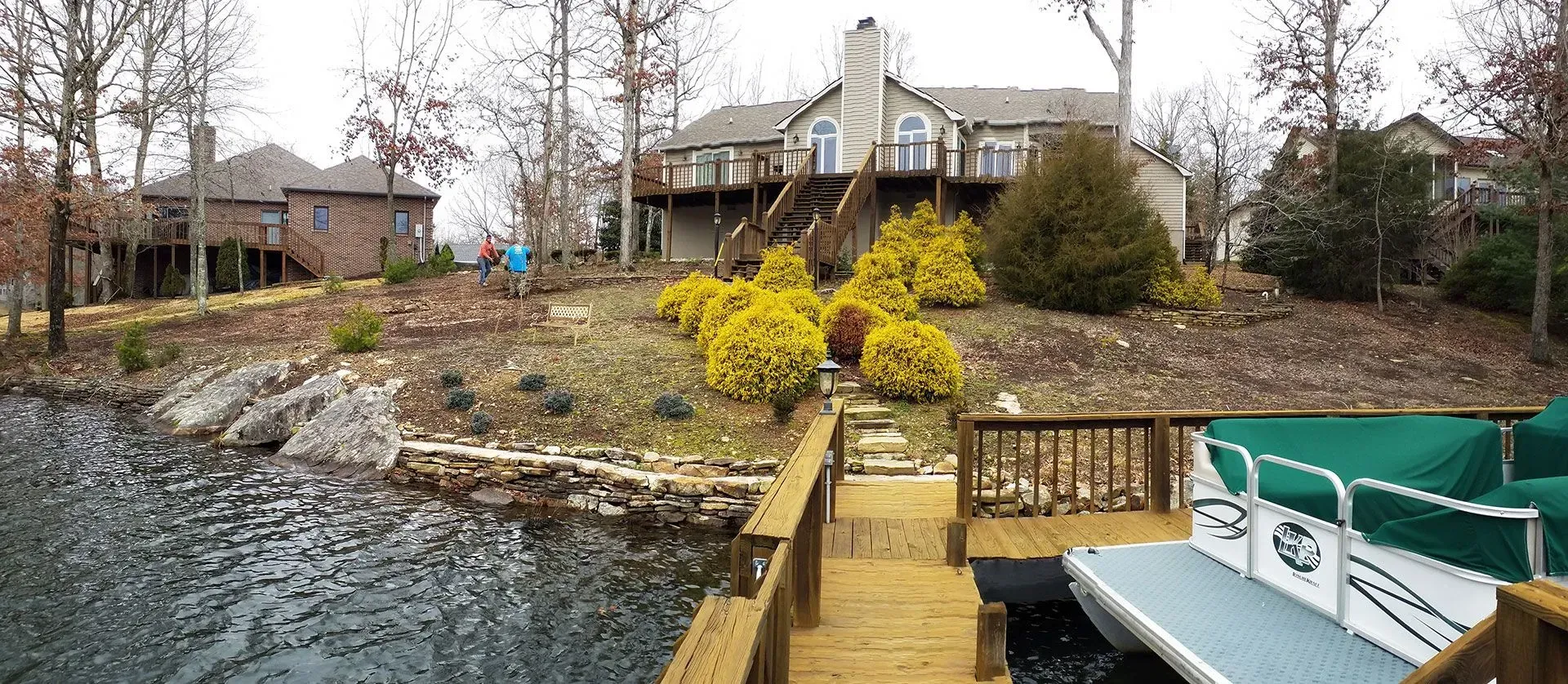 A boat is docked at a dock in front of a large house.