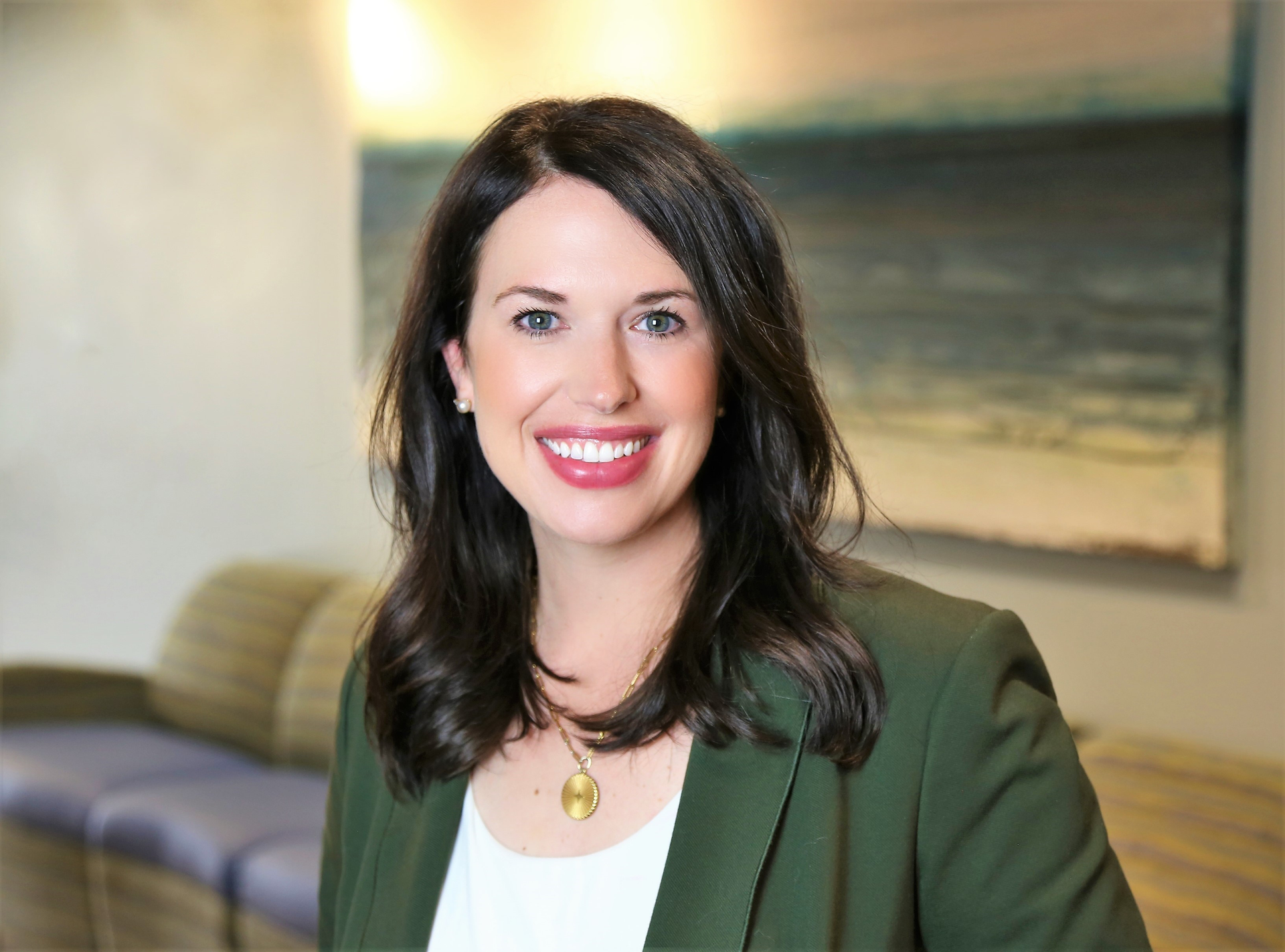 a woman in a green jacket and white shirt is smiling for the camera .