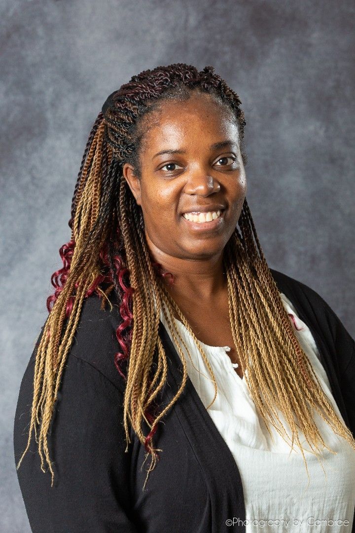 a woman wearing a gray jacket and earrings is smiling for the camera .
