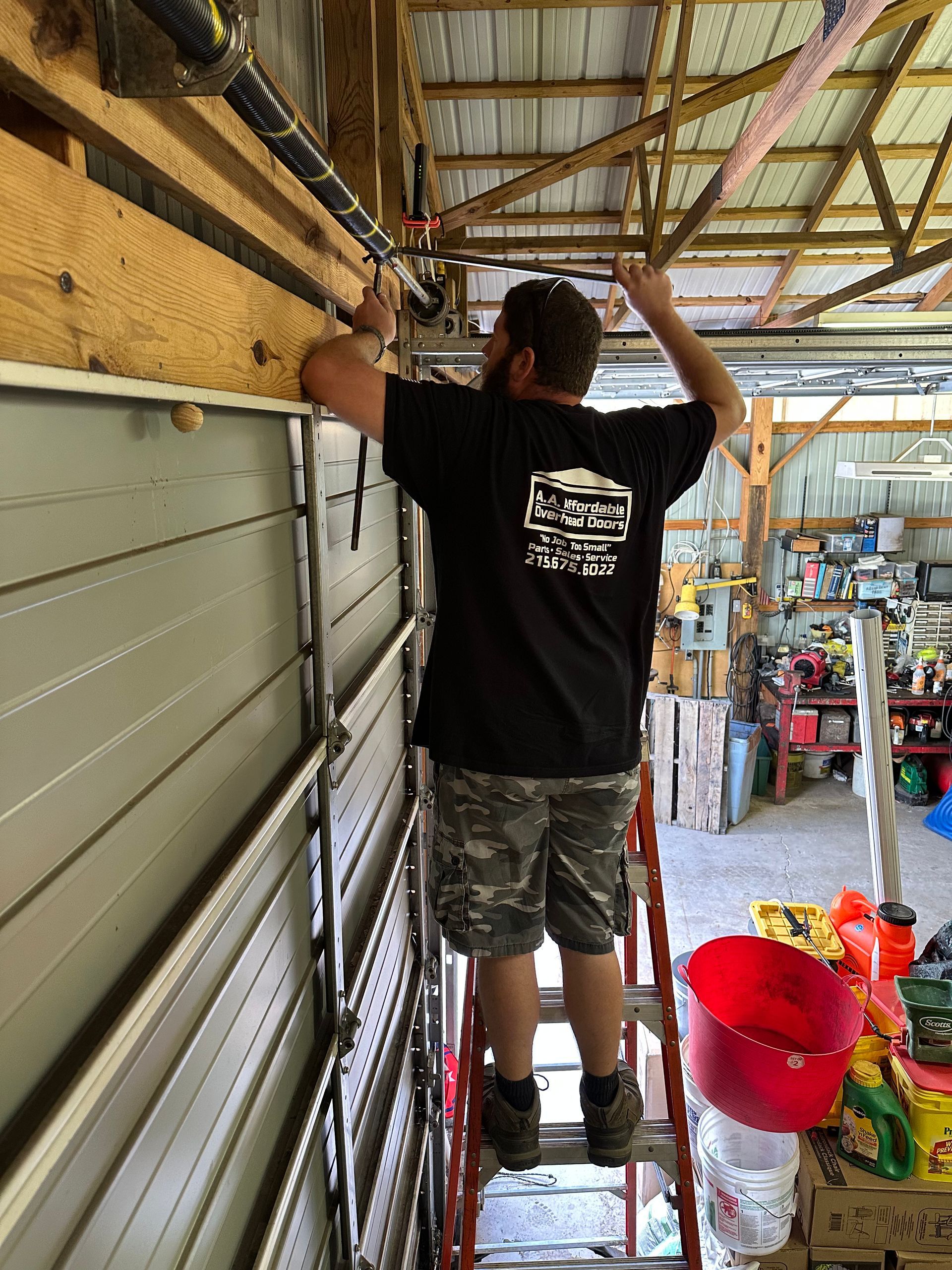 Man using a wrench to repair a garage door spring, indoors.