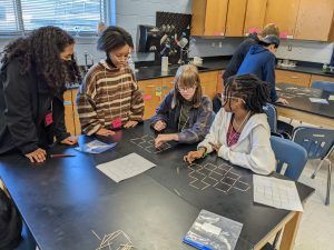 A group of children are sitting around a table in a lab.