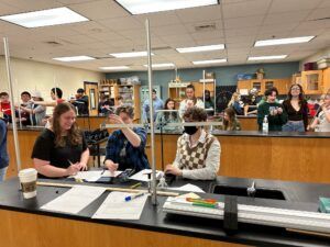 A group of people are sitting at a table in a classroom.