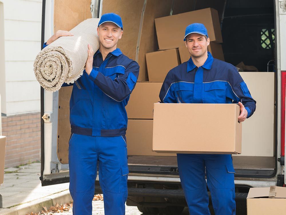 Two men in blue uniforms carefully moving boxes as professional movers in Santa Venetia, CA.