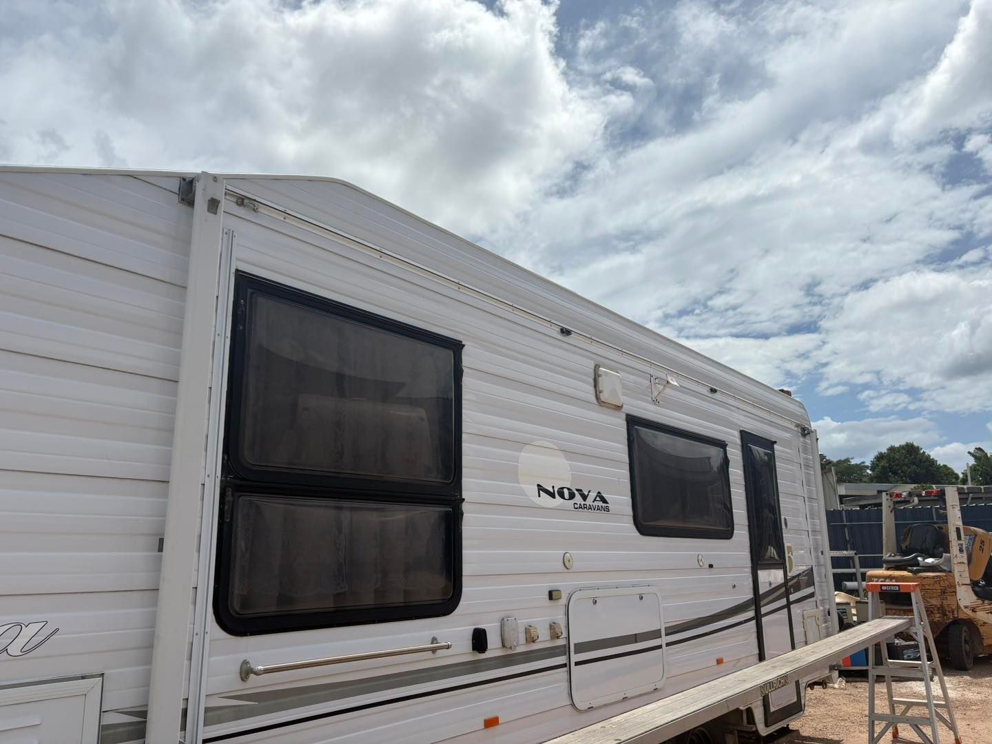 White RV with dark-tinted windows under a partly cloudy sky.