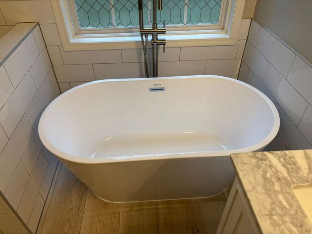 A white bathtub is sitting in a bathroom next to a window.