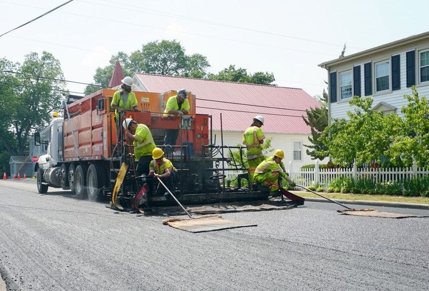 Slurry seal paver and crew placing slurry surfacing.
