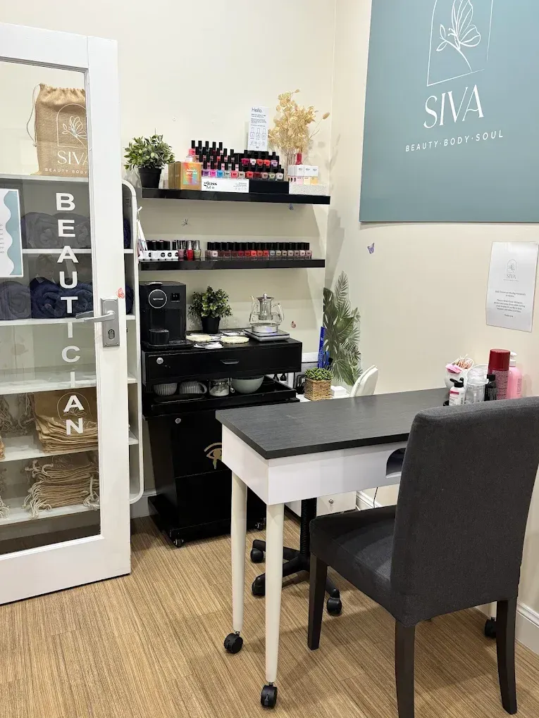 Nail salon interior with manicure station, black rolling cart, shelves of nail polish, and a door with 