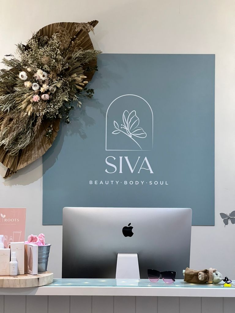 Reception desk at Siva Beauty Body Soul with logo, iMac, and floral arrangement.