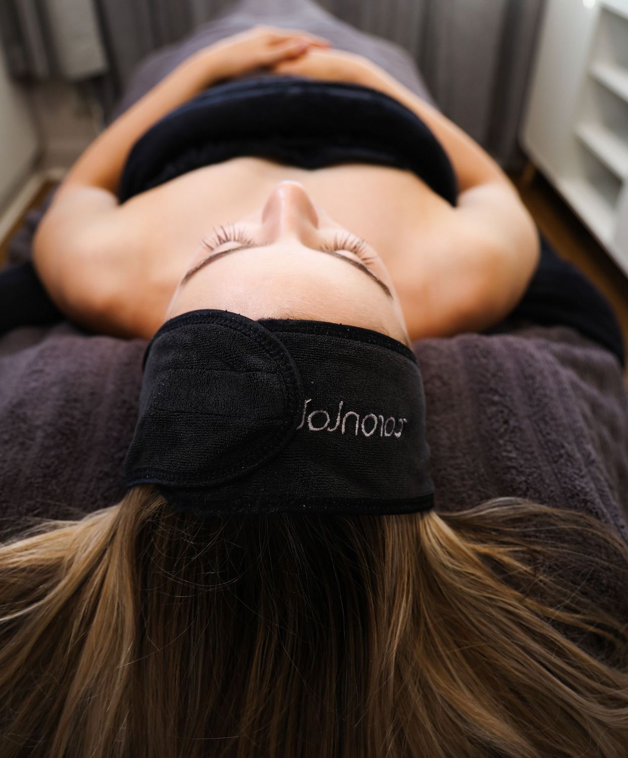 Person lying on a massage table, wearing a black headband.