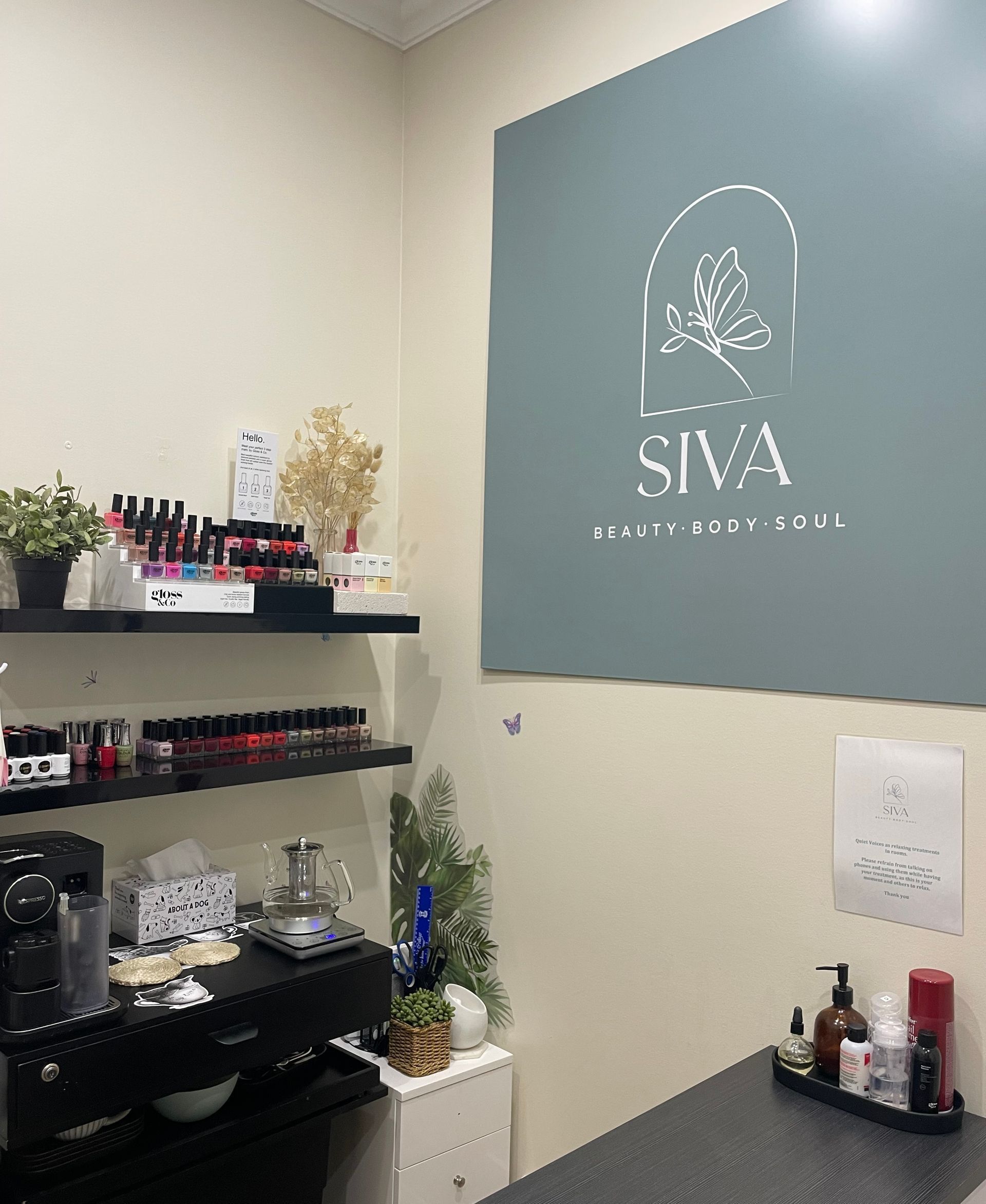 A beauty salon corner with a sign that reads 'Siva Beauty & Brows Clinic' and shelves with nail polish and other supplies.