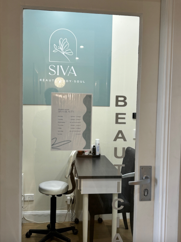 A beauty salon interior with a desk, chair, and signage with the name 