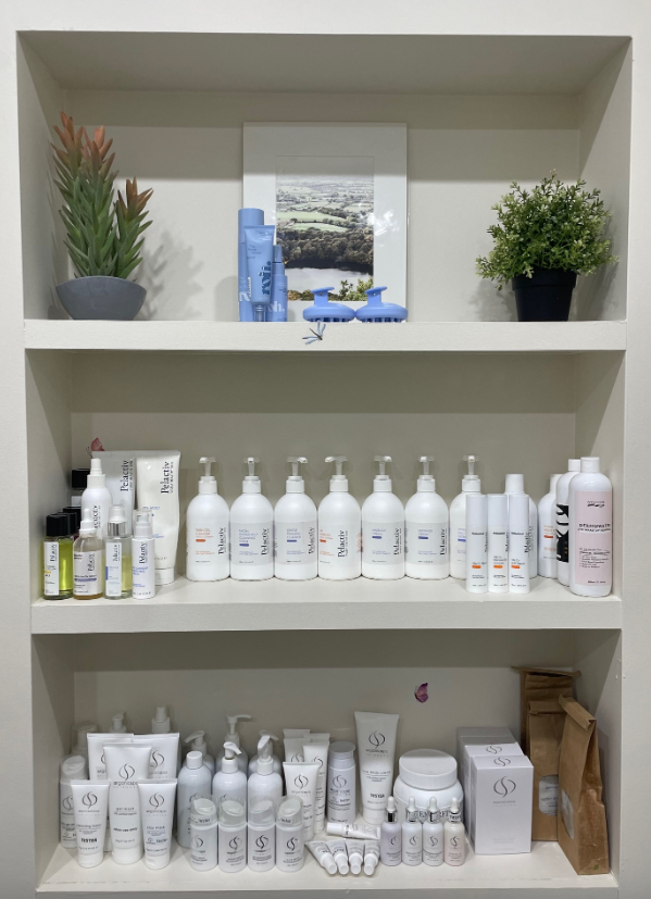 White shelves displaying skincare products, decorative plants, and a framed art piece.