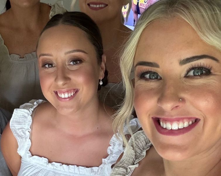 Group of smiling women wearing white tops, close-up shot.