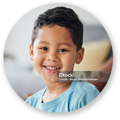 Smiling child in a blue shirt, looking directly at the camera.