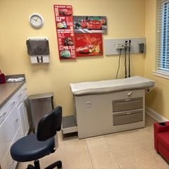 Pediatrician's office exam room with a medical bed, a chair, and