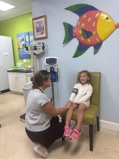 A medical professional examining a young girl in a medical office.