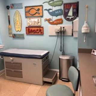 Examination room with beach-themed decor and a medical examination table.