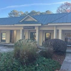 Exterior view of a commercial building with dark blue roof, beige walls, and landscaping.