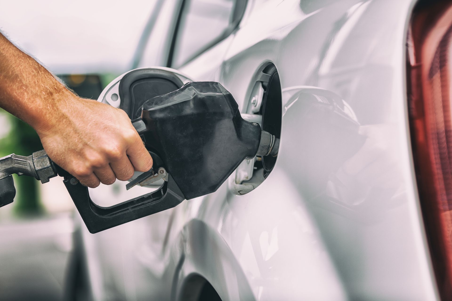 A man is pumping gas into a car at a gas station.