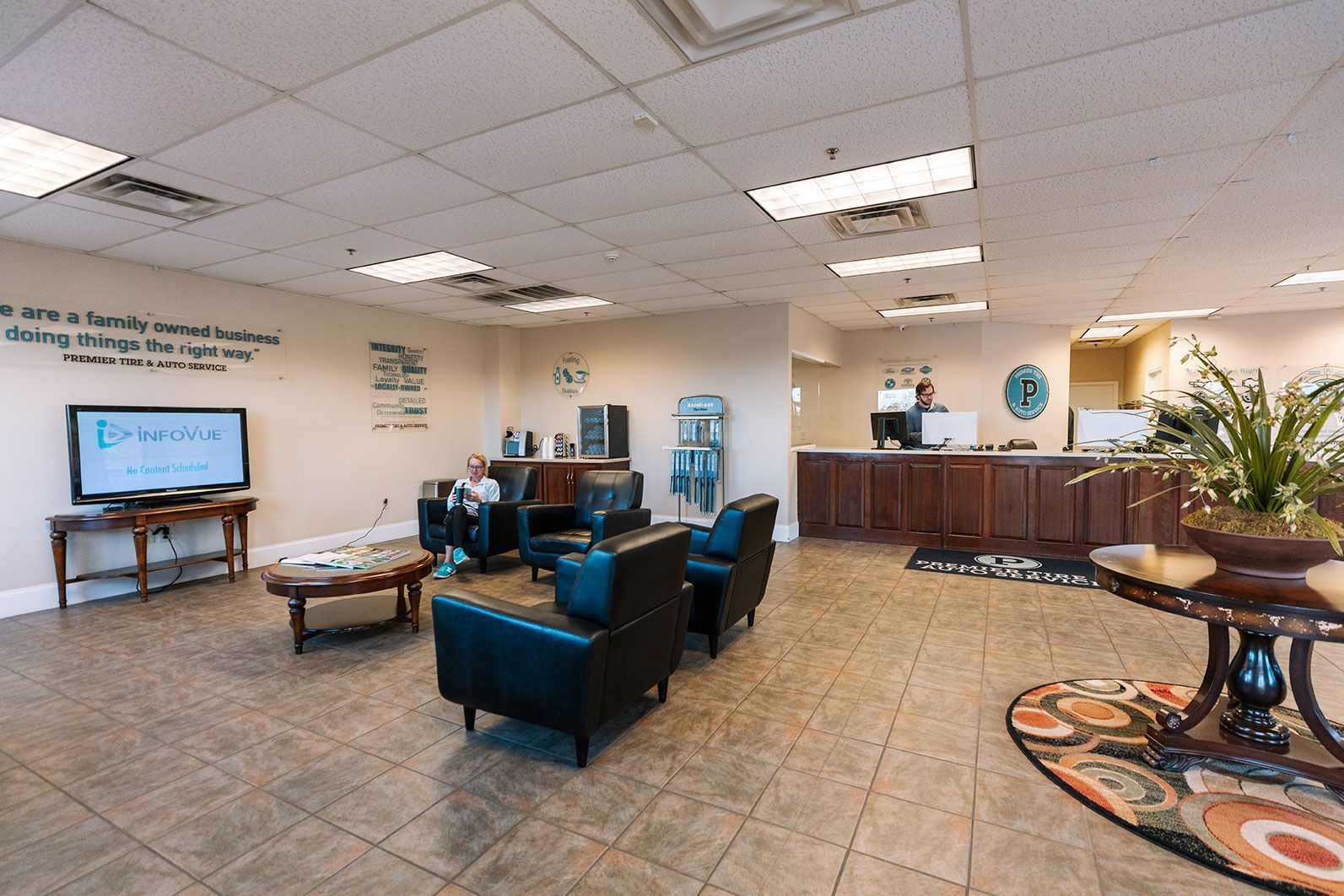 A man is sitting on a couch in the waiting room of Premier Tire