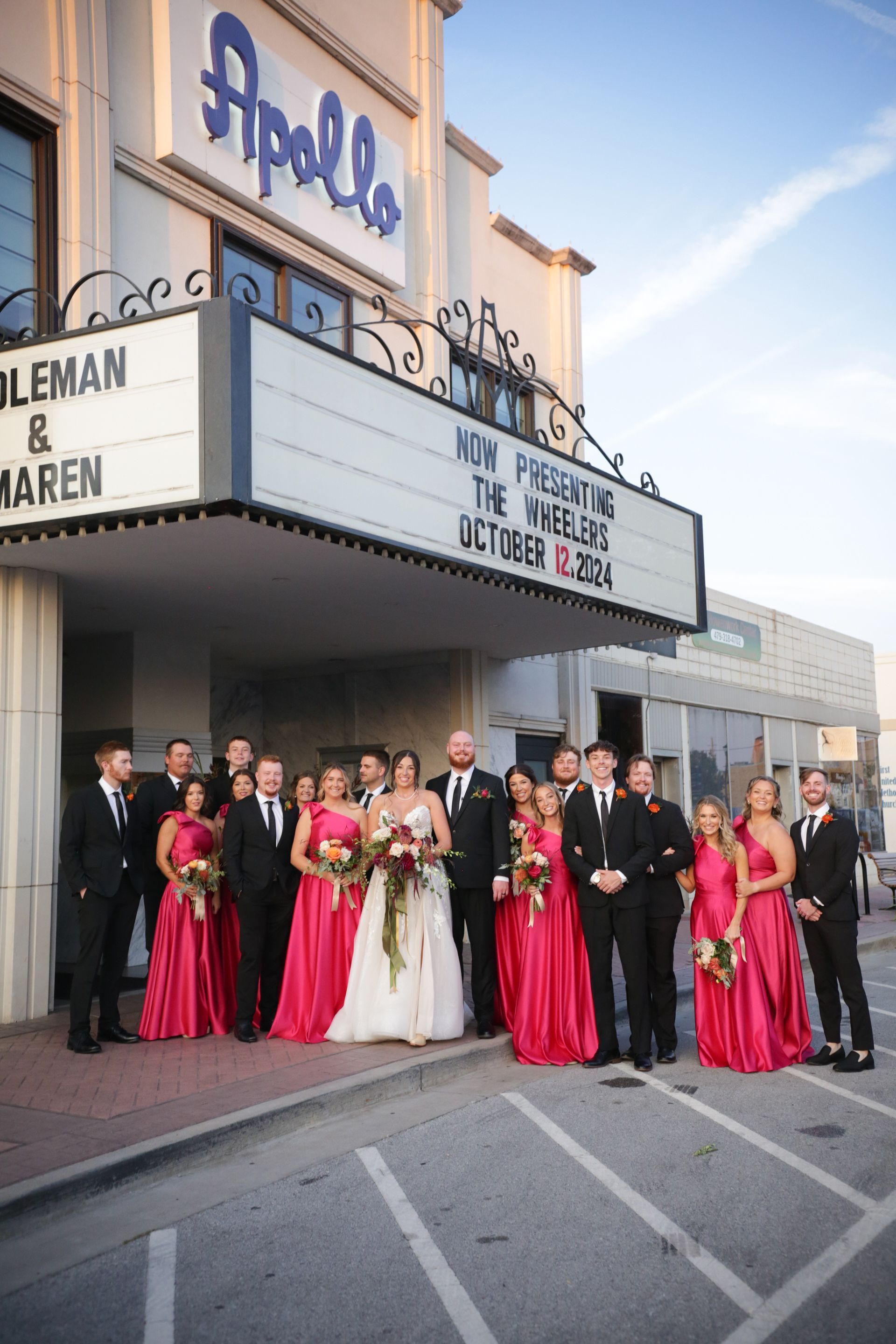Wedding party posing in front of the Apollo Theater, bride in white dress, bridesmaids in pink, groomsmen in black.