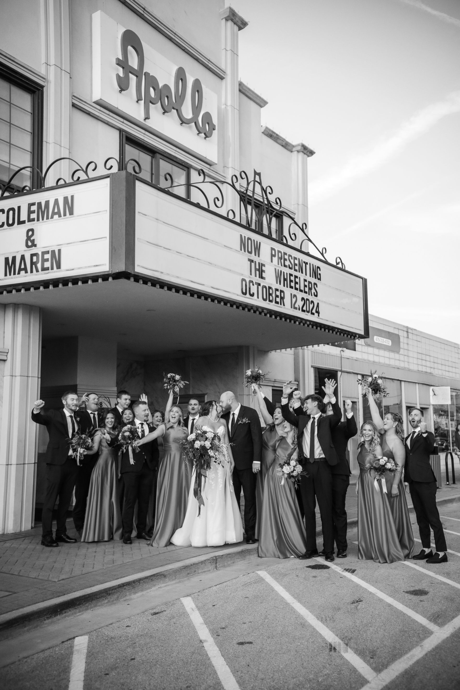 Wedding party outside Apollo Theater, raising arms in celebration. Marquee reads 