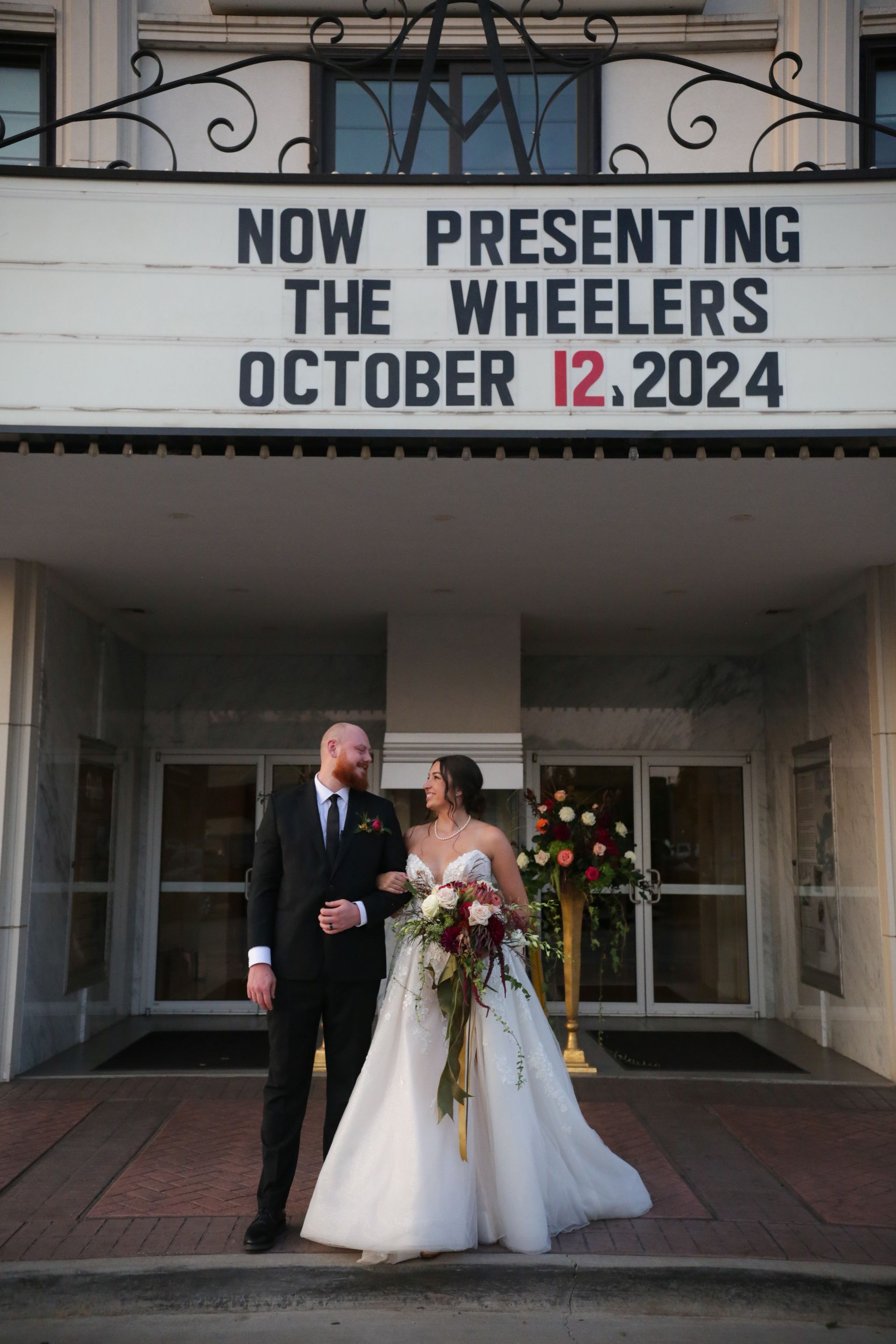 Wedding couple in front of a theater marquee that reads 