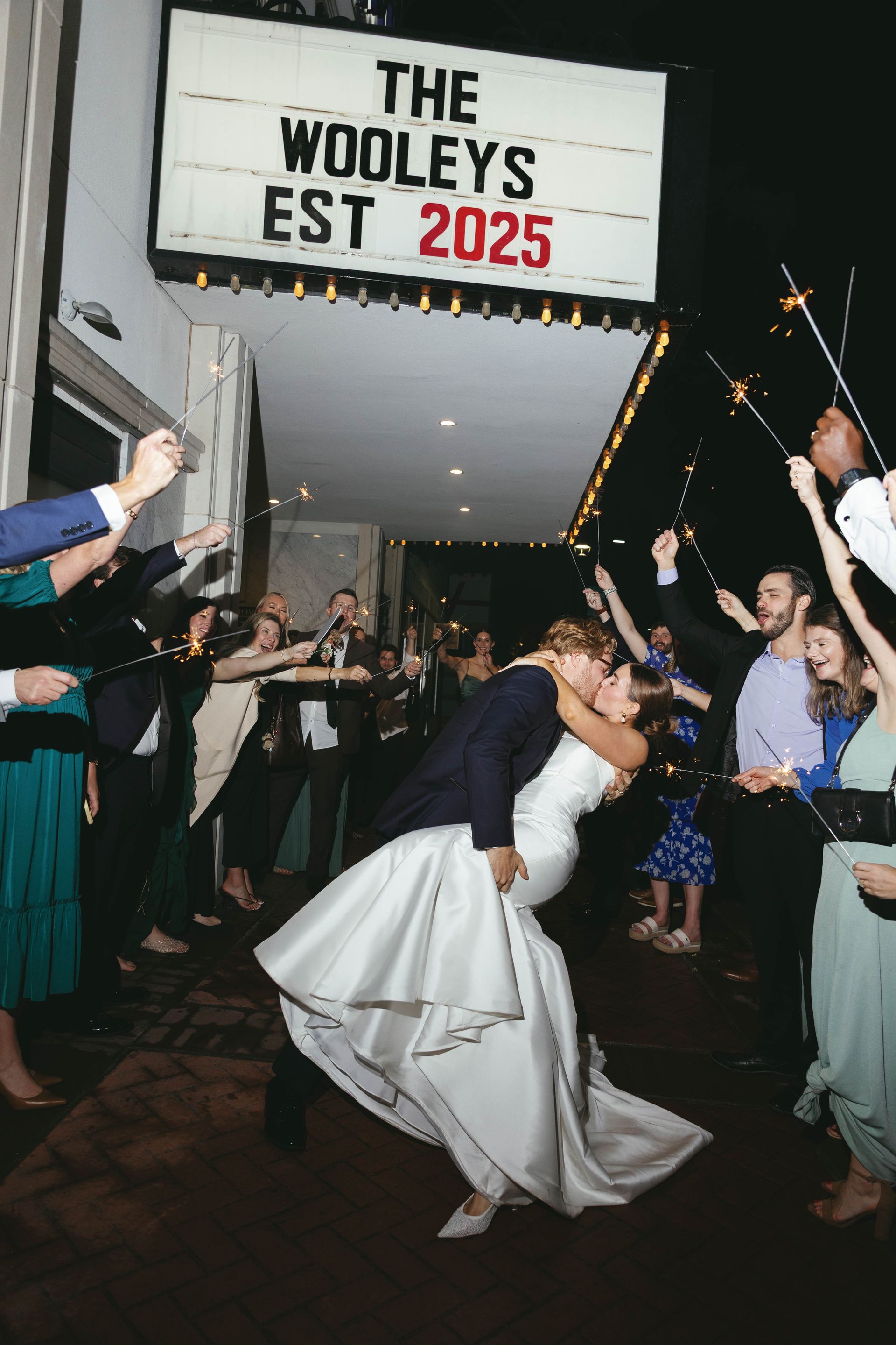 Newlyweds kissing under a sign: 