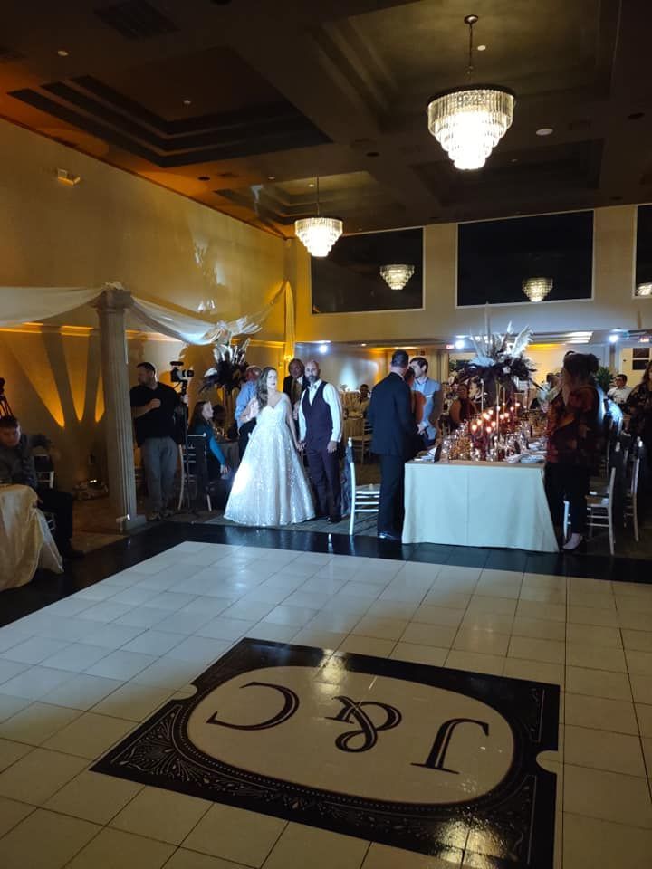 Wedding reception with couple on dance floor, guests, and decorated tables in a venue.
