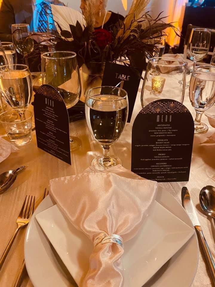 Formal table setting with pink napkin, menu card, and centerpiece.