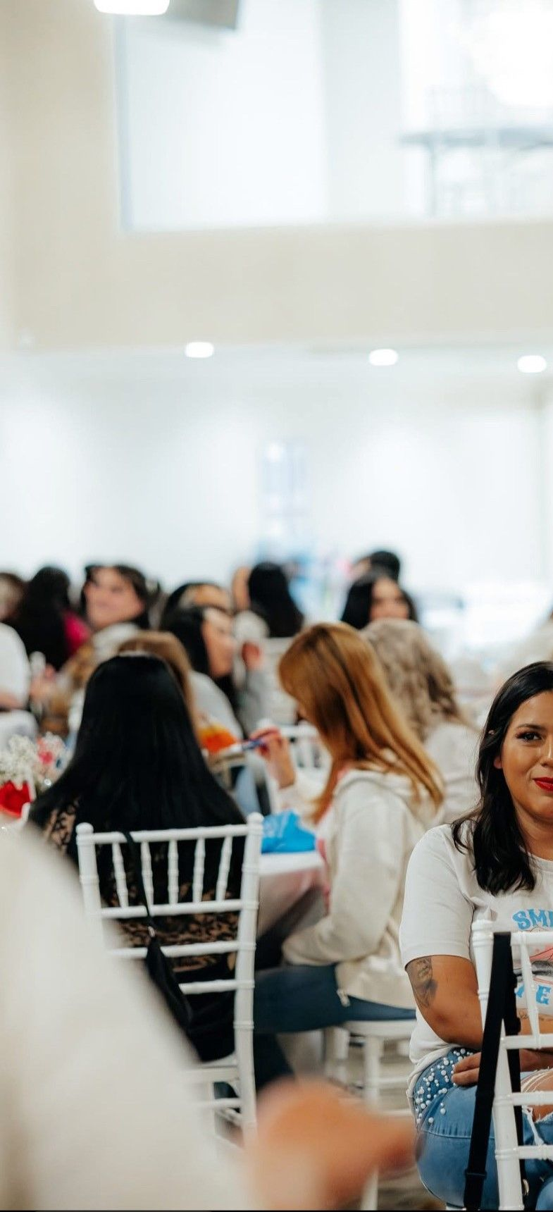 People seated at tables in a brightly lit room. Some are eating, others are looking around.