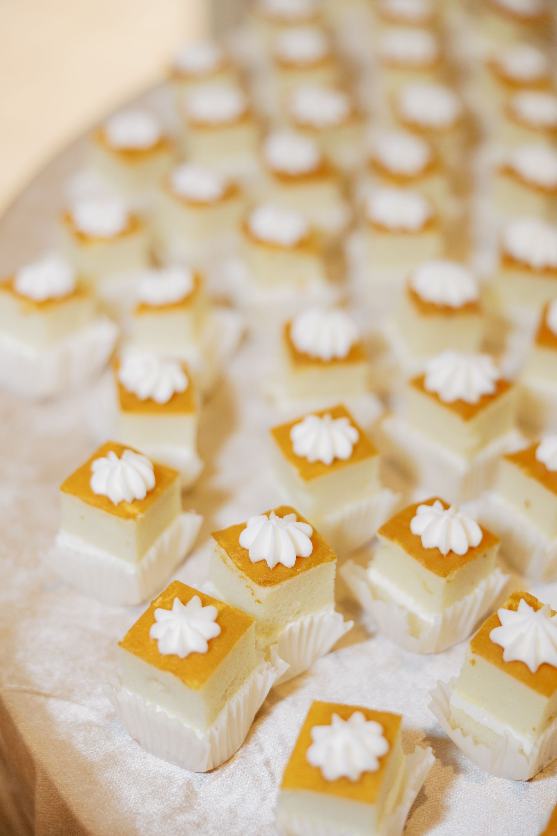 Mini square pastries with white frosting on a tray.