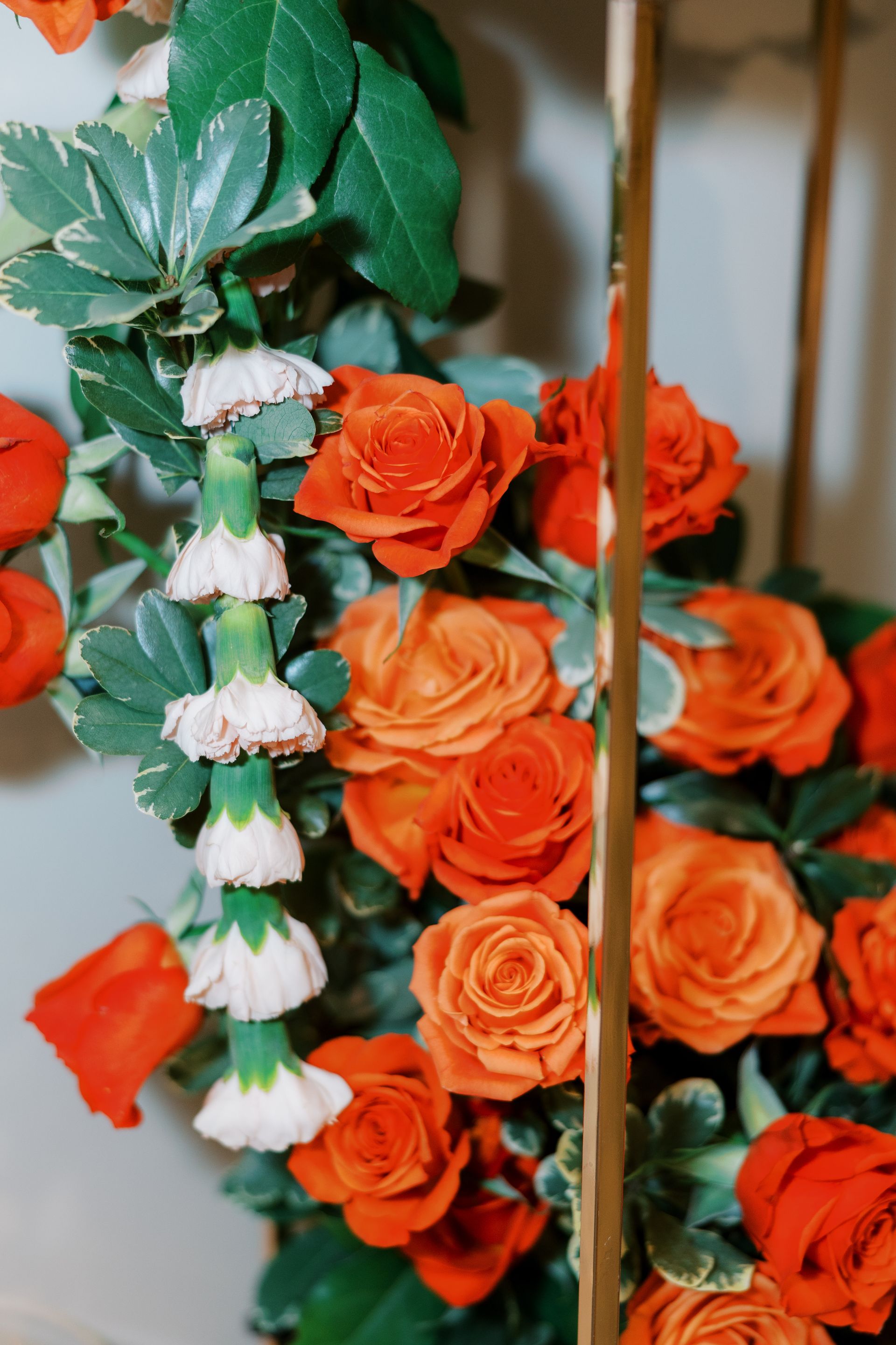 Orange roses and white flower garland with green foliage.