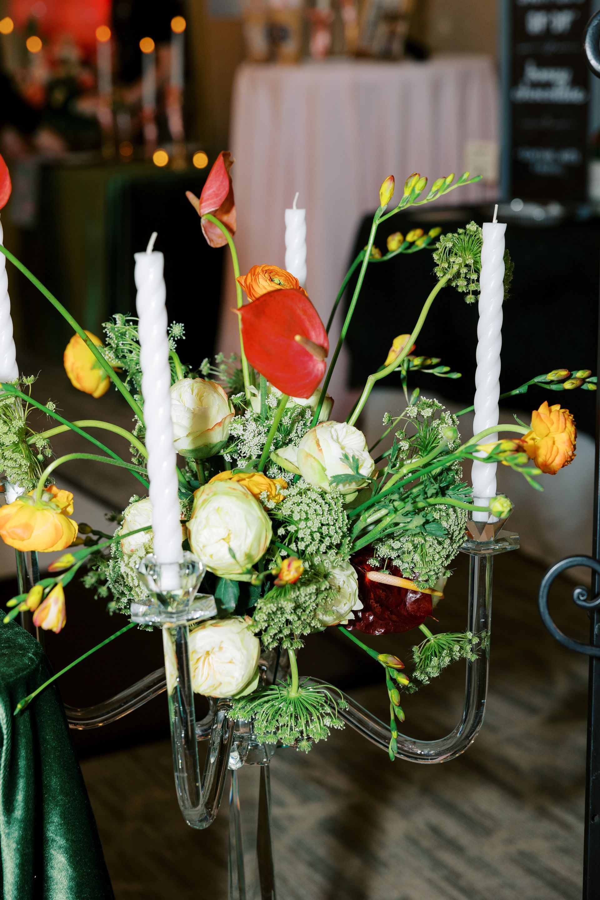 Candle holder with white candles and a floral arrangement of white and yellow flowers.