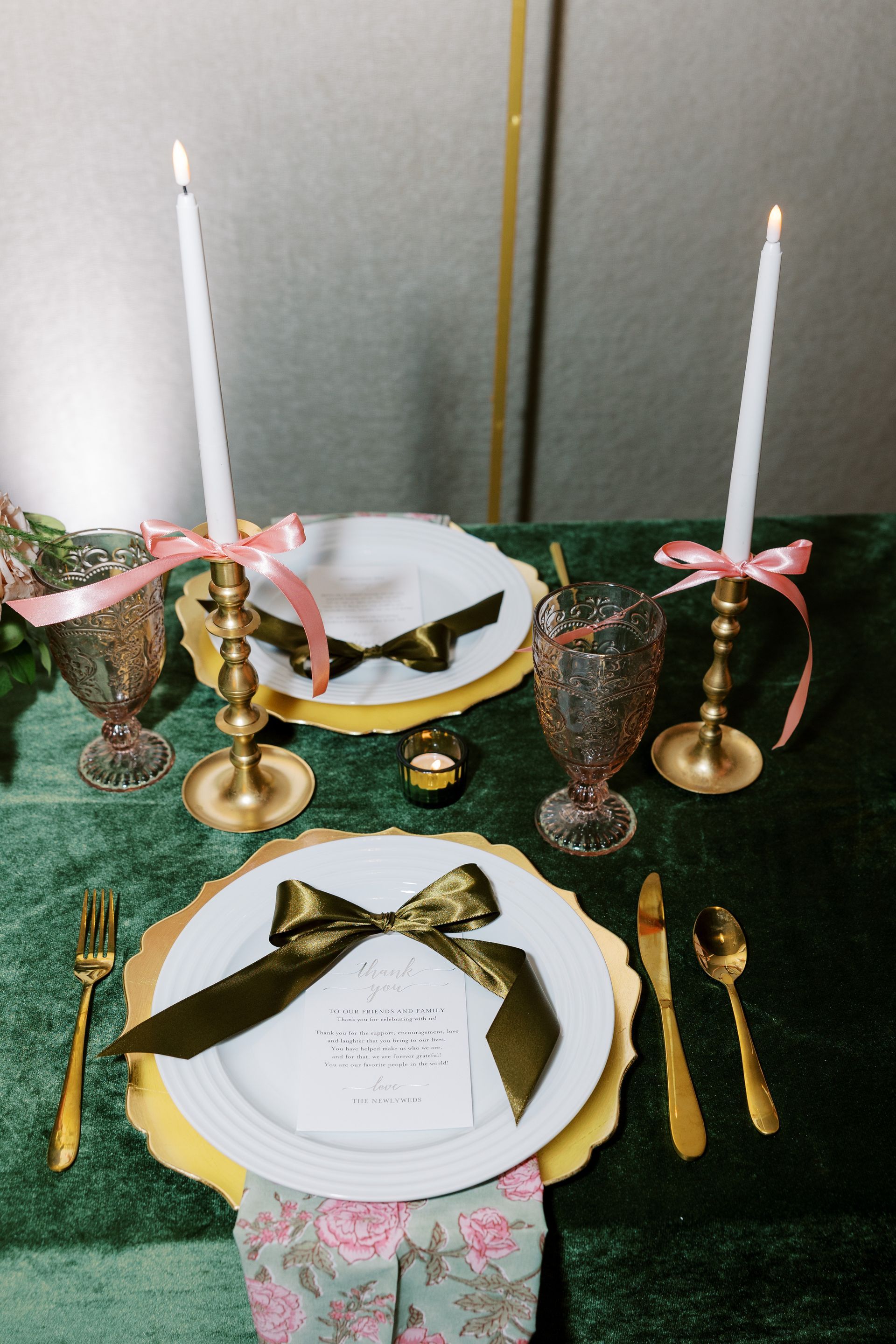Formal table setting with gold accents, candles, and ribbon.