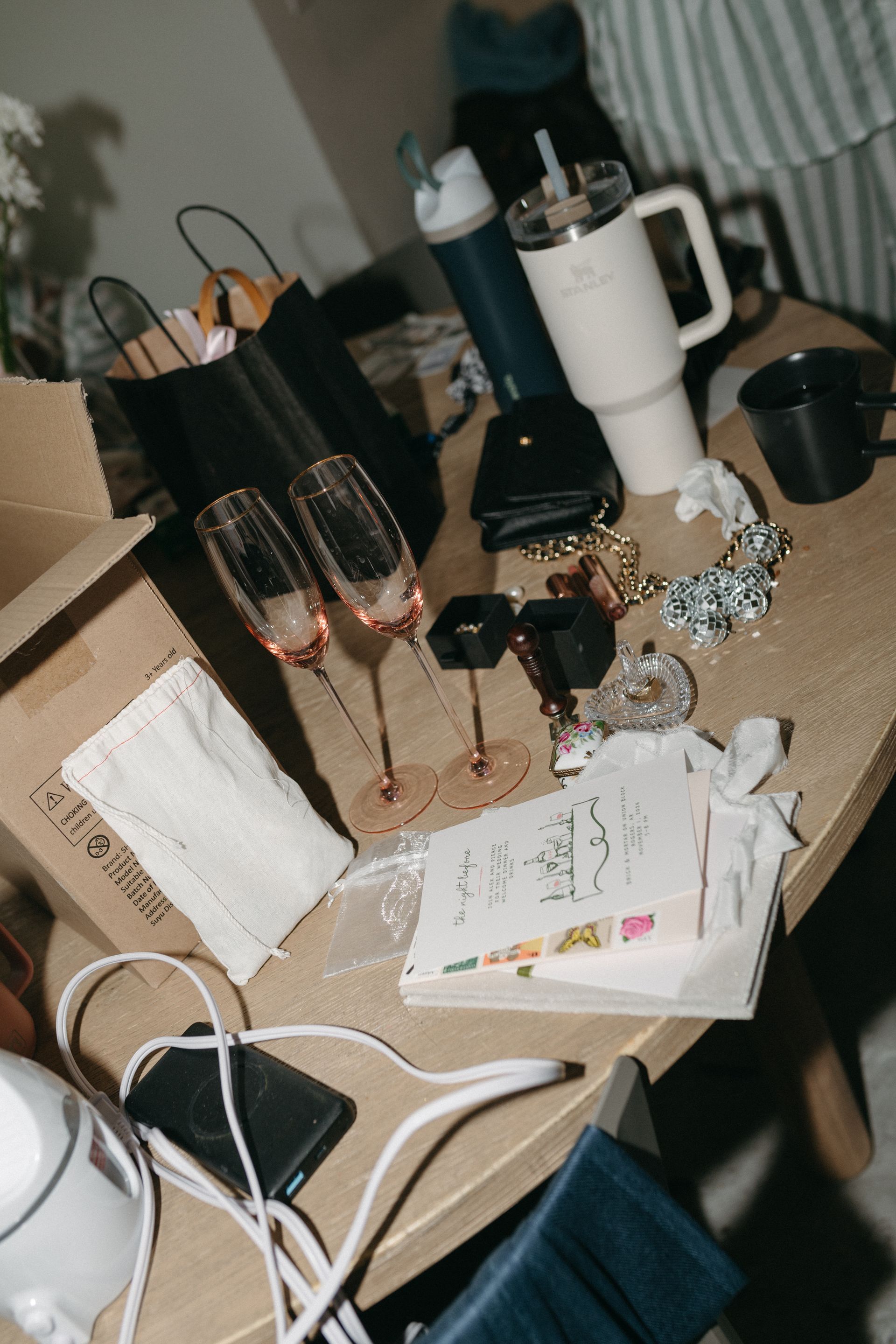 Table with champagne glasses, a water bottle, gifts, and a pair of white high heels.