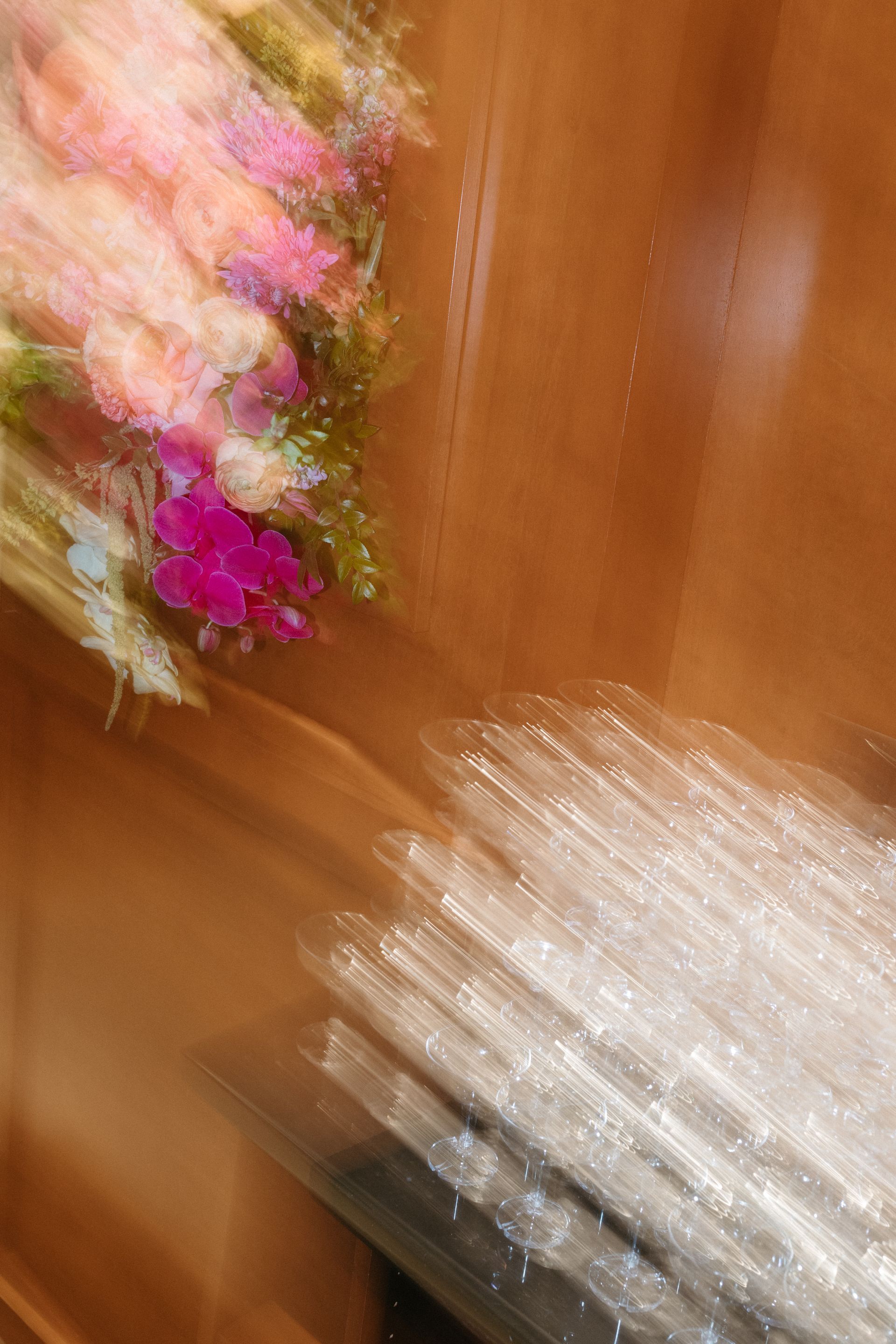 Blurred view of flowers in pinks and purples, brown background with a white, streaked lower section.