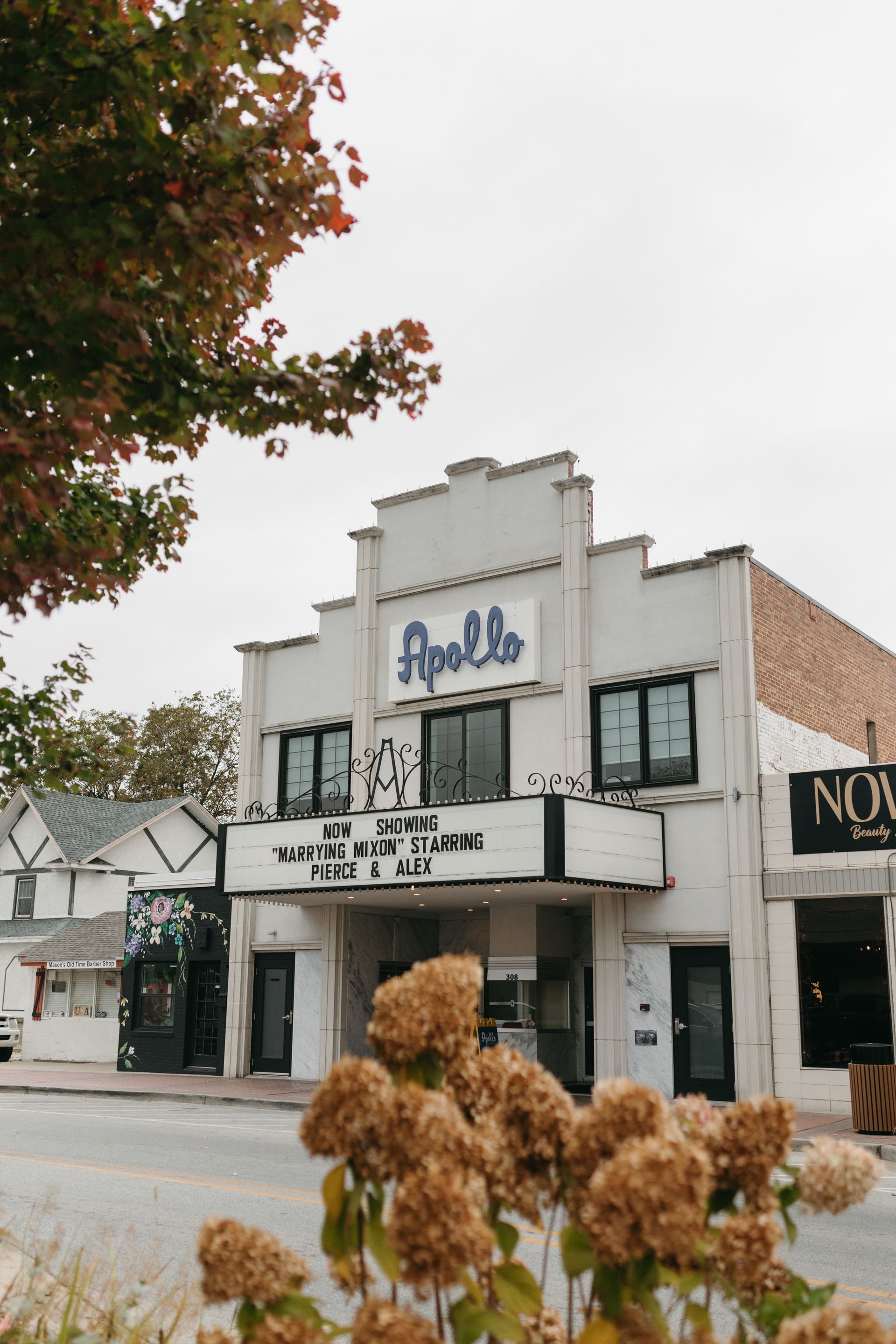 Apollo Theater, white art deco building with marquee and blue neon sign, autumn foliage.