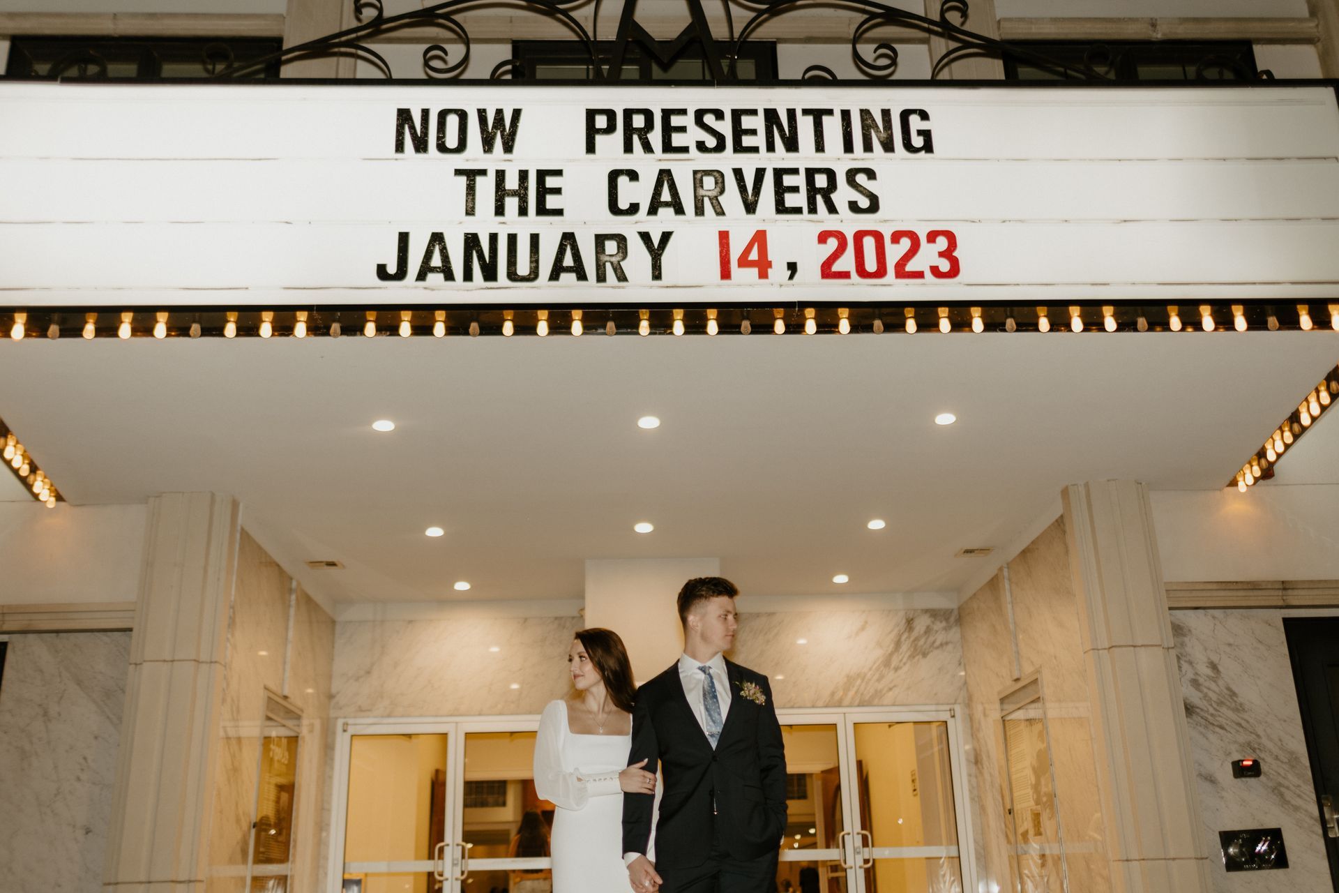 Couple exiting a theater, marquee reads 