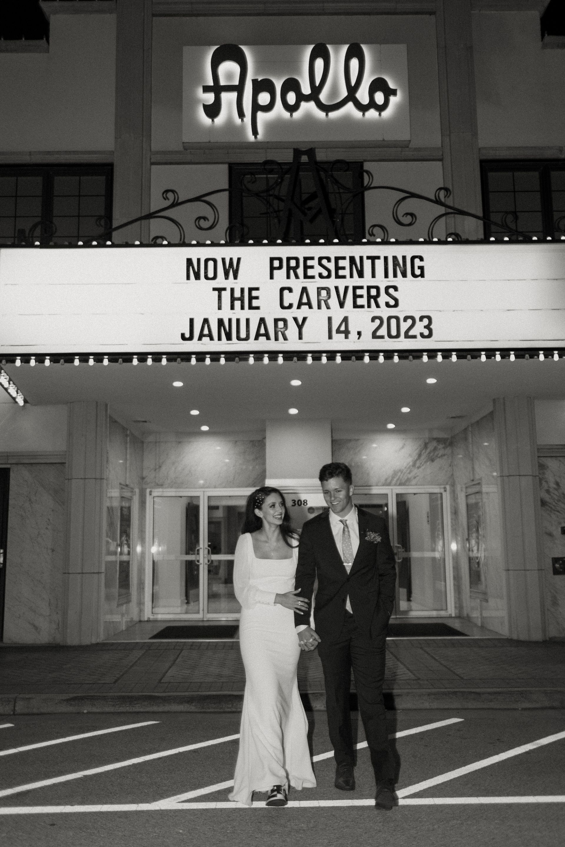 Couple walks in front of the Apollo Theater, marquee reads: 