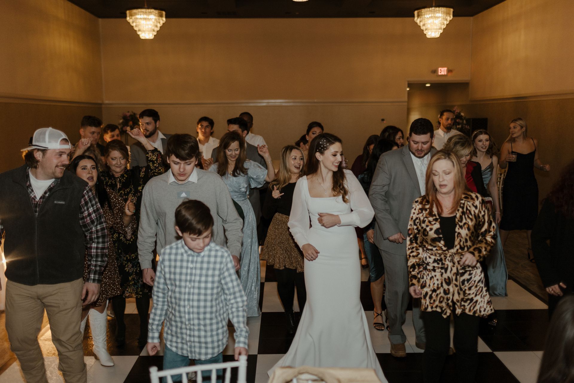 People dancing at a wedding reception on a black and white checkered dance floor.