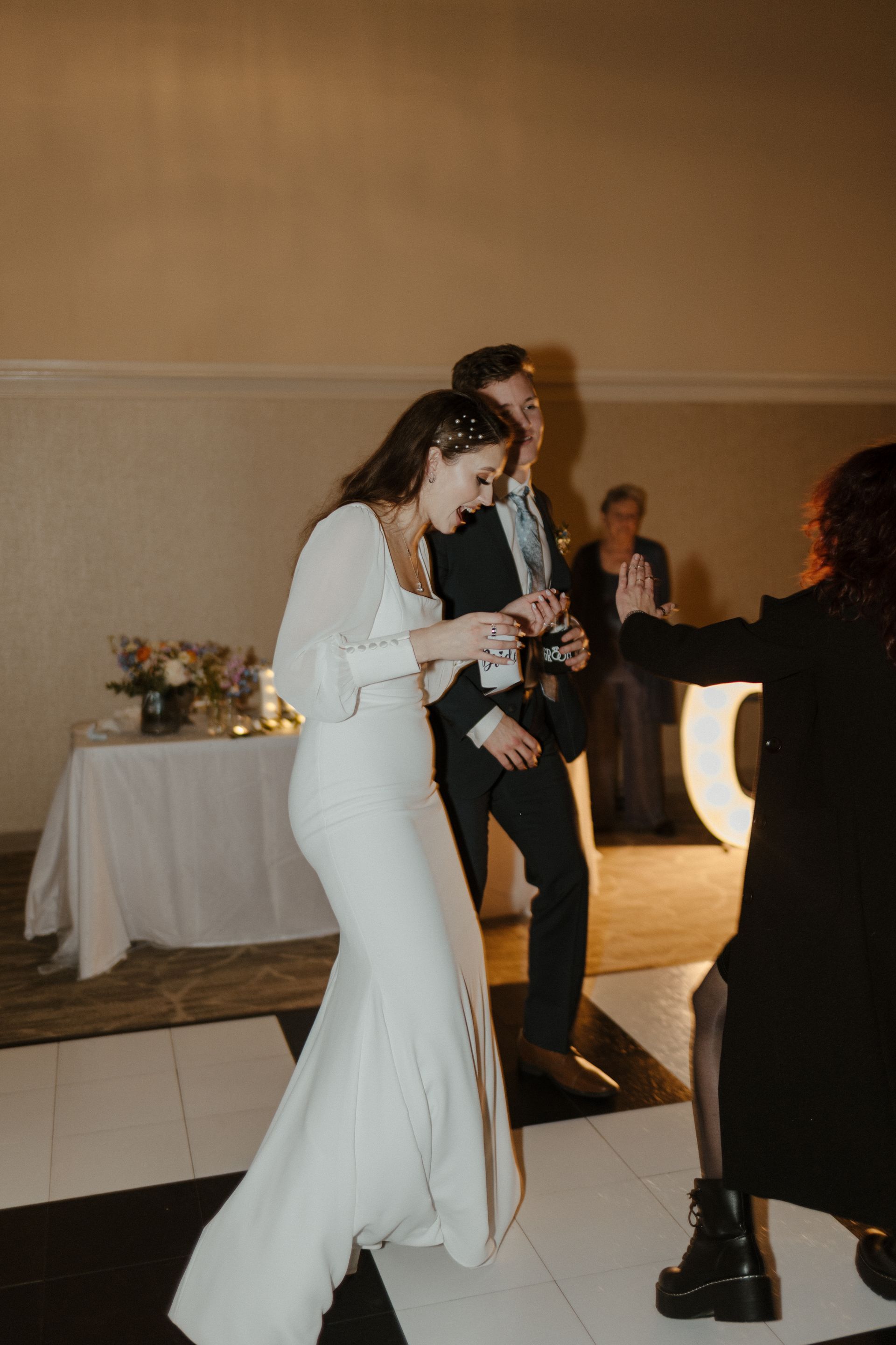 Bride and groom dancing at a wedding reception on a black and white checkered dance floor.