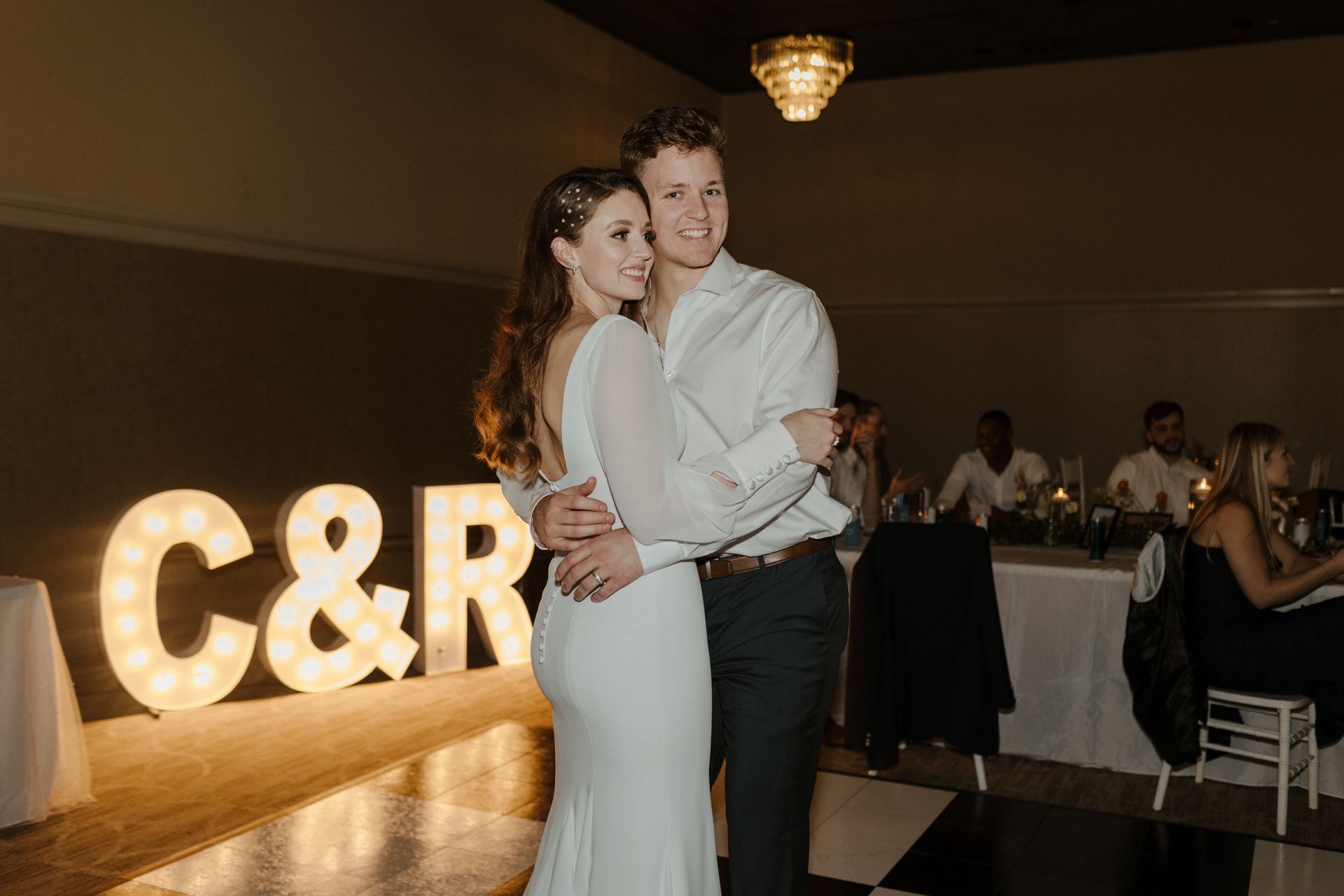 Newlyweds embrace at a reception. Marquee letters 