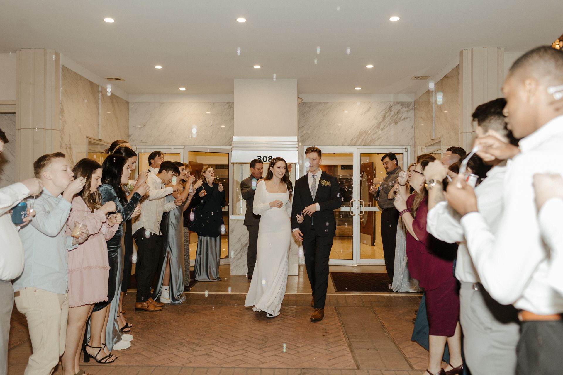Newlyweds walk through guests, who are applauding and throwing confetti.