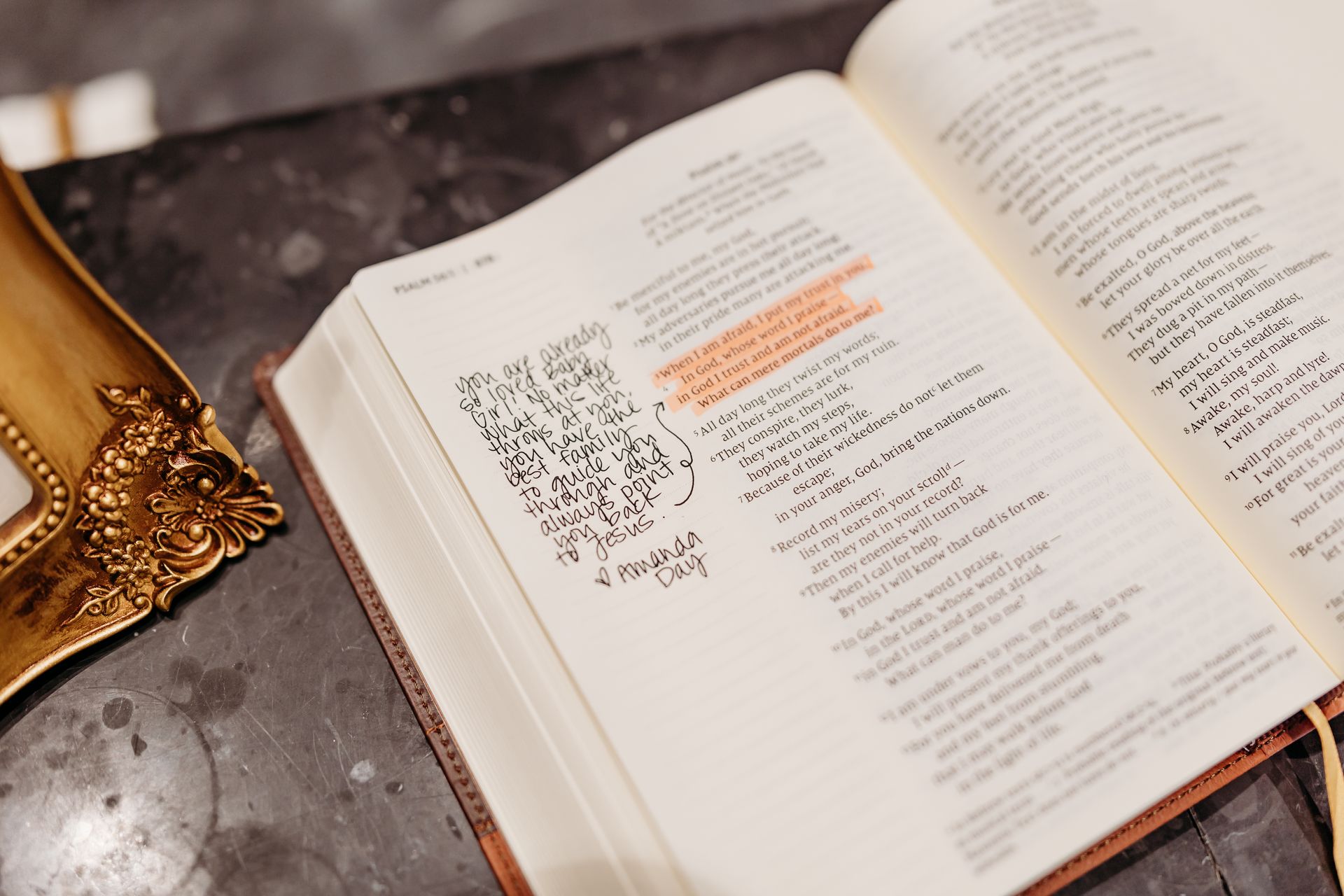 Open book with highlighted text; a framed item rests on a table.