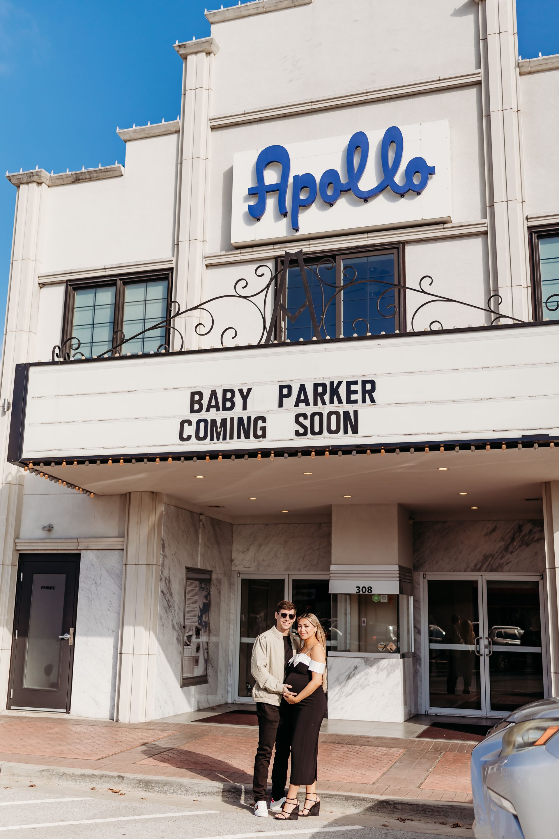 Couple posing in front of the Apollo Theater with marquee reading 