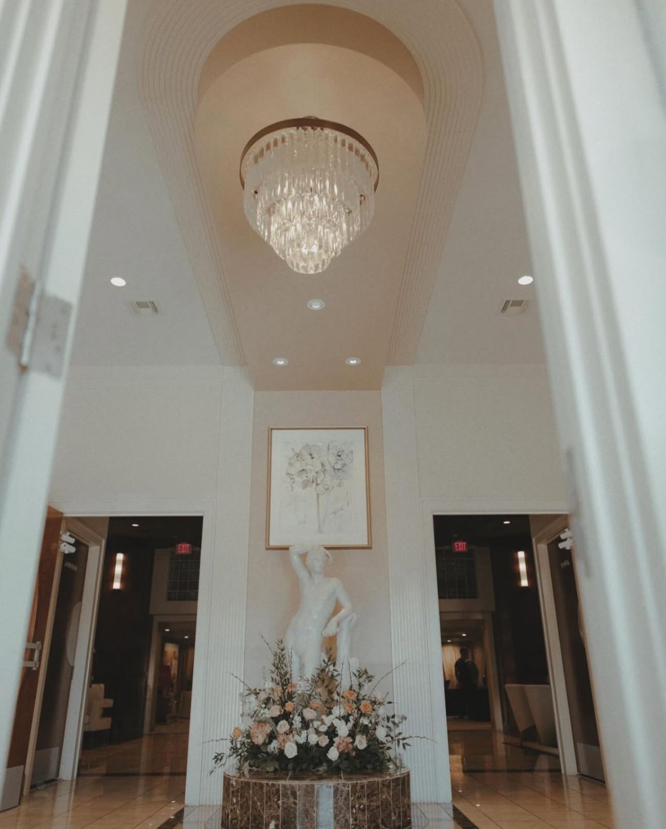 Elegant interior with chandelier, statue, and floral arrangement.