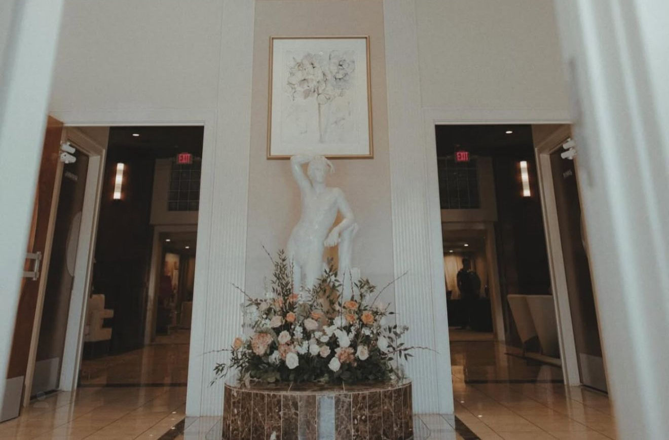Elegant interior with chandelier, statue, and floral arrangement.