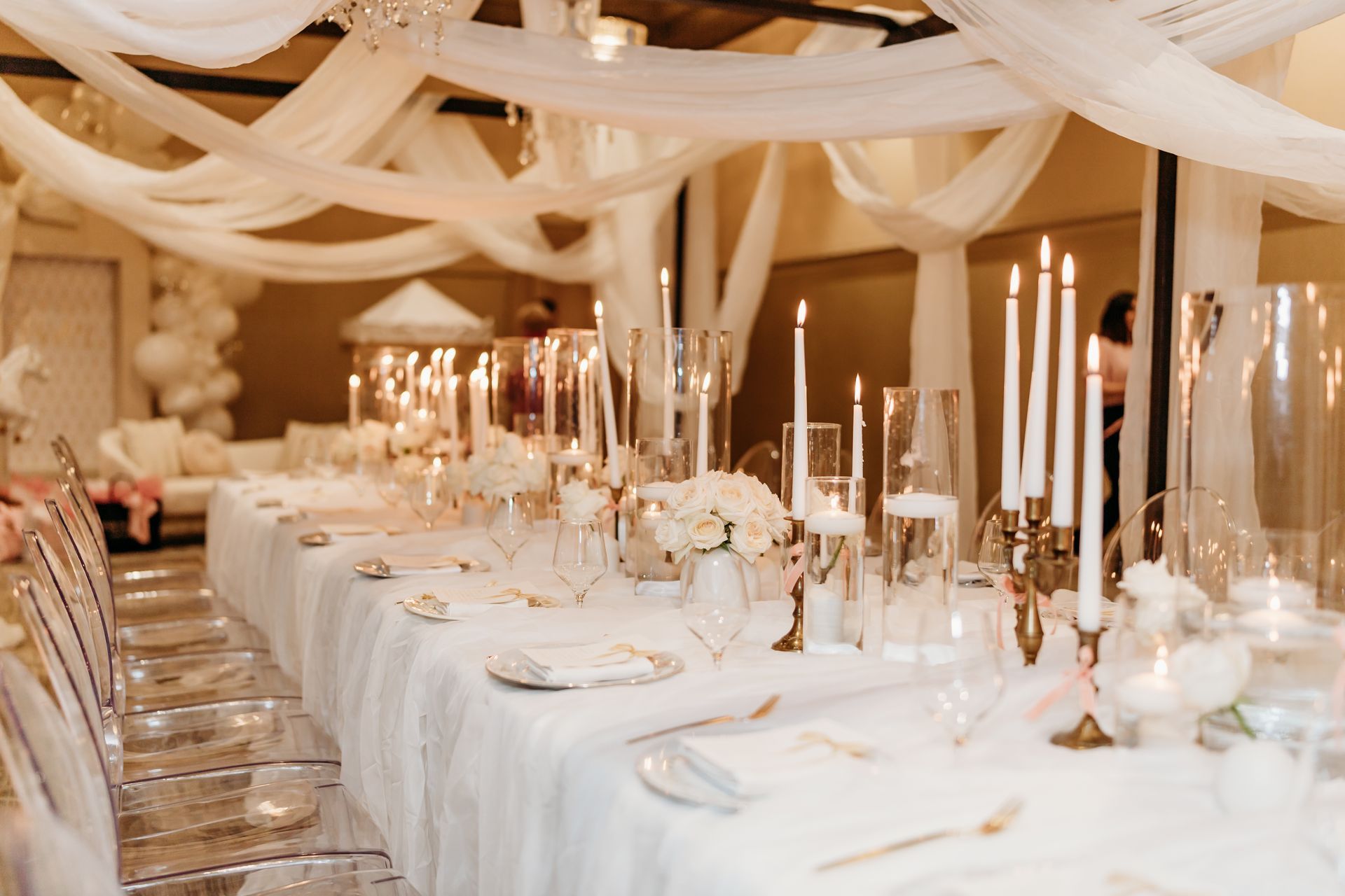 Elegant dining table set for a celebration. White linens, candles, and floral arrangements.