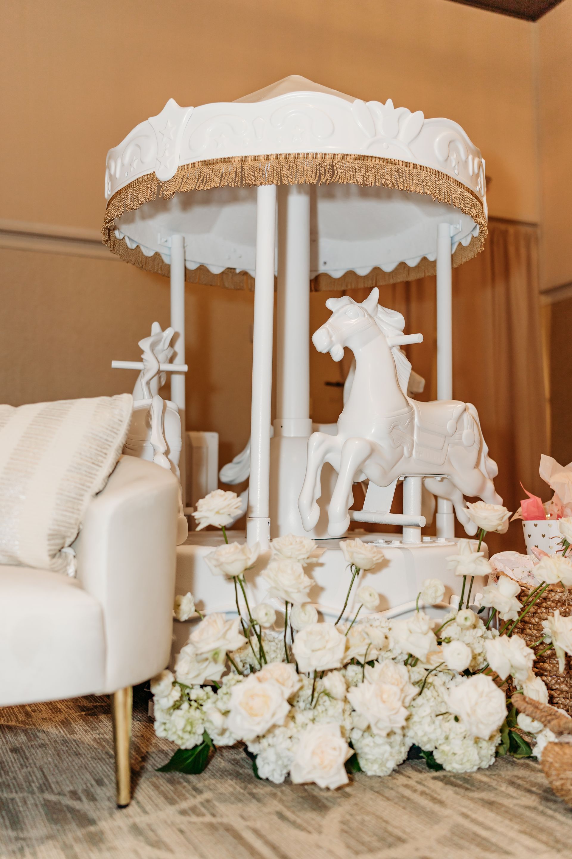 White carousel decorated with white flowers and a gold trim.